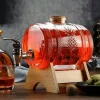 Vibrant red glass barrel-shaped beverage dispenser with embossed pineapple design, silver faucet, on wooden stand.