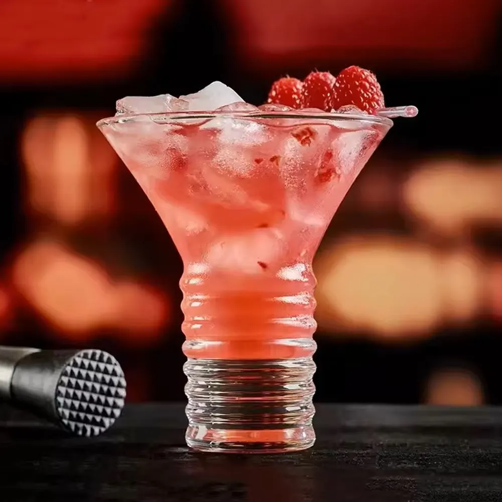 Twisted Martini Glass with an 8 oz capacity, featuring a textured stem, filled with a pink fruit-flavored cocktail garnished with raspberries on a skewer, set against a dimly lit background.