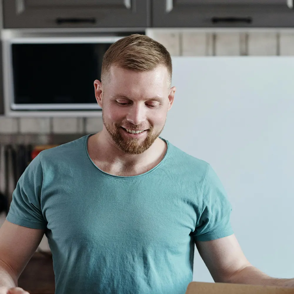 An individual happily looking down at the products they just received in a box, showcasing the assurance and joy of premium drinkware backed by a 100% satisfaction guarantee.