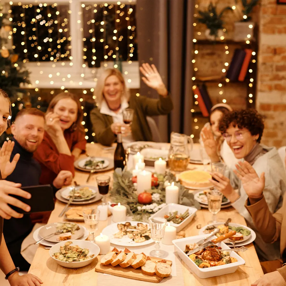 A group of individuals gathered around a dining table filled with various dishes, glasses, and candles, creating a cozy and festive atmosphere, showcasing the versatility and innovative design of premium drinkware for any beverage.