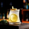 340 ml Vertical Elegance short glass with unique hunched design and vertical ridges, filled with a yellow drink and garnished with a lemon slice.