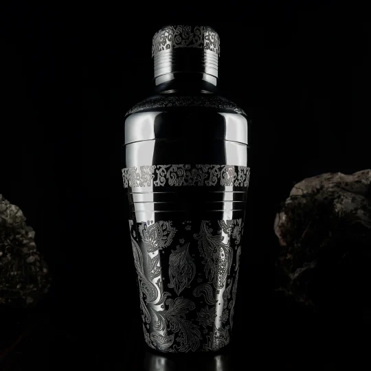 17 oz Engraved Stainless Steel Cocktail Cobbler Shaker positioned between two rocks on a dark background