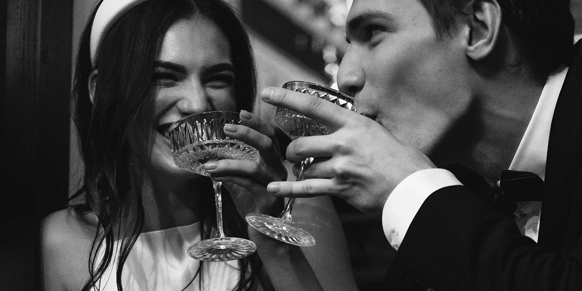 Two people holding and clinking ornate crystal glasses in a celebratory toast, capturing an elegant and sophisticated moment.